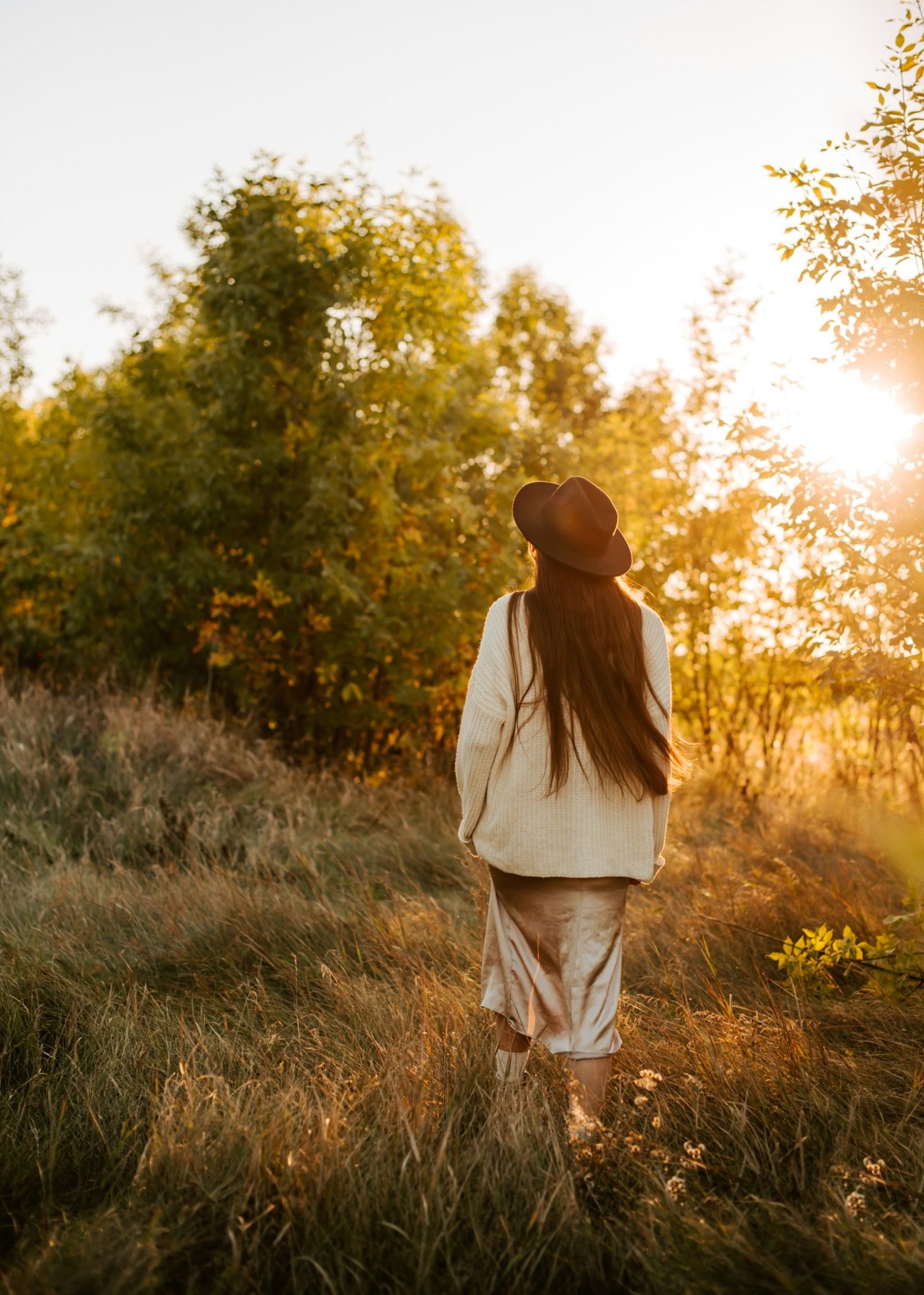 A woman walking through a sunlit autumn landscape