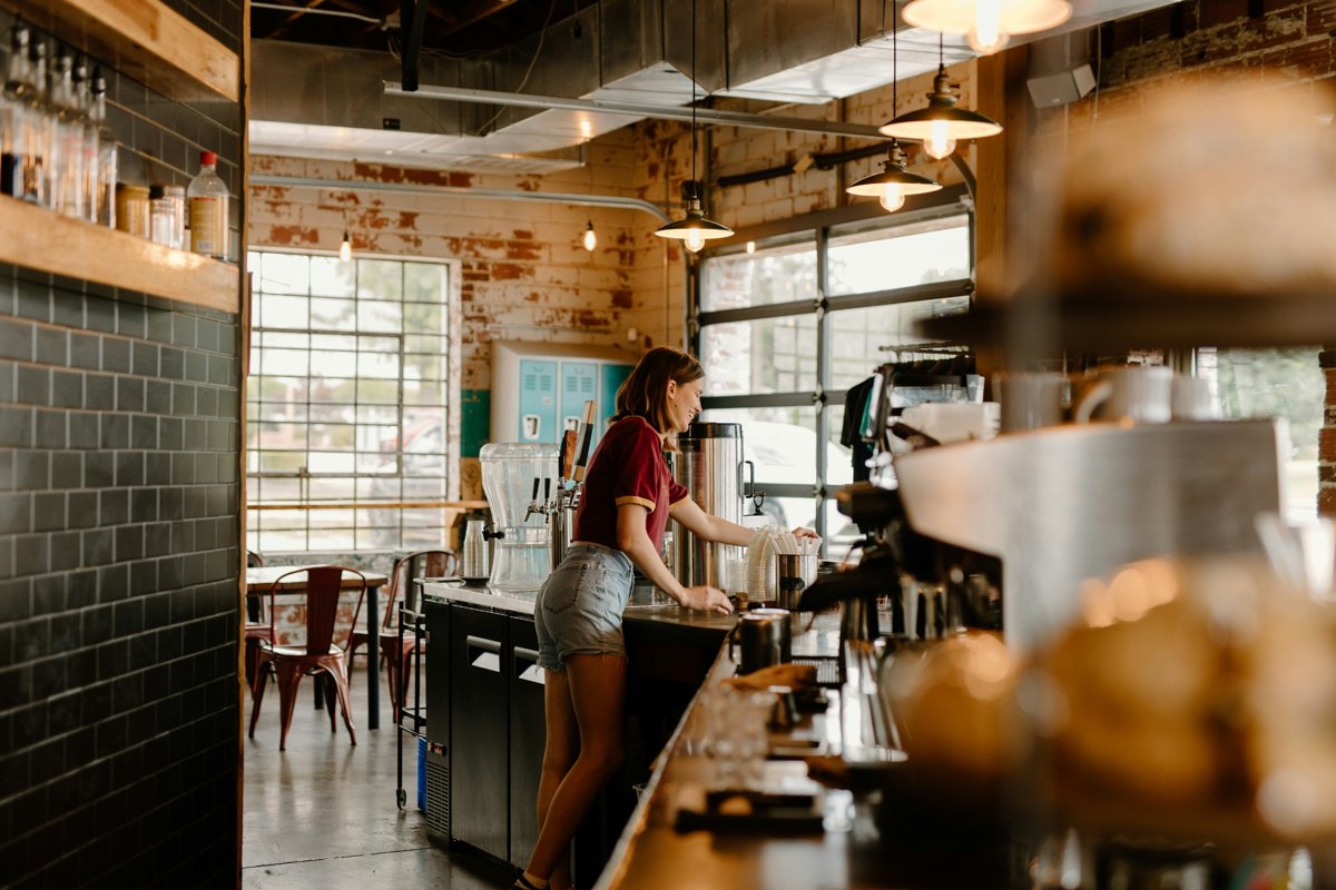 A welcoming café with warm wood details and a barista at work